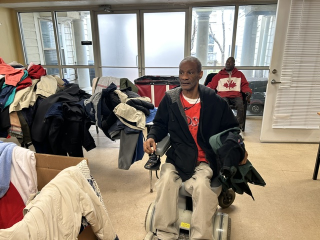A man in a wheelchair selects his coat from the table of donated jackets and rain gear at Welcome House in Atlanta.