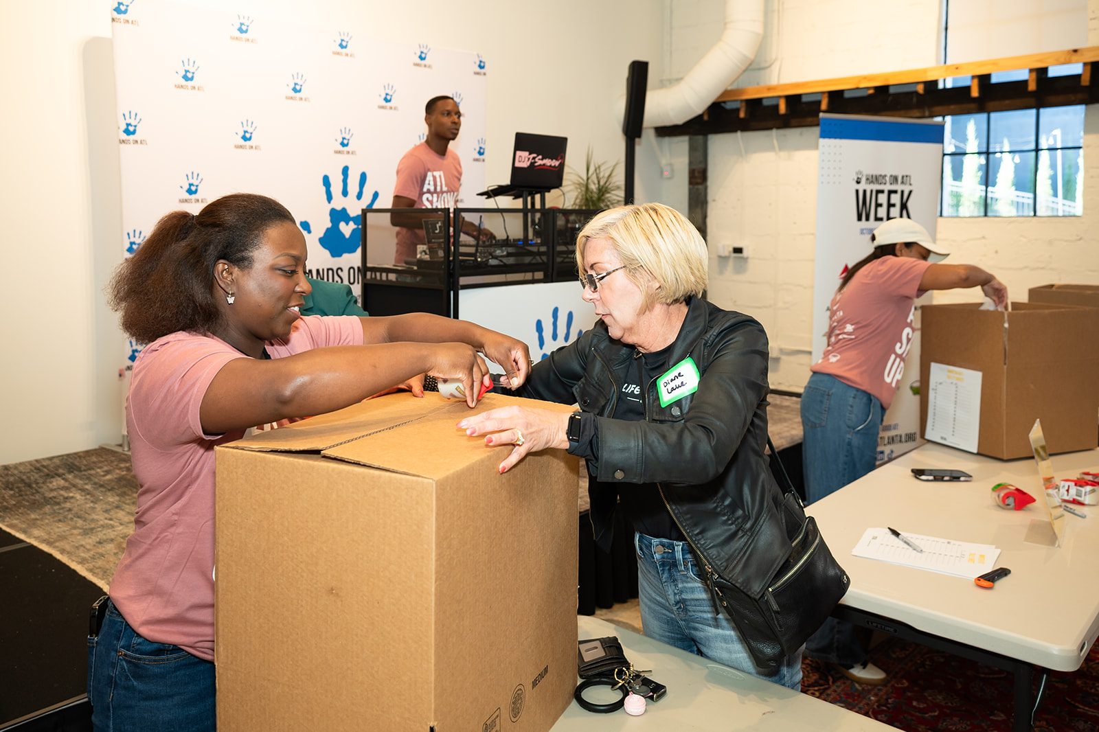 Two volunteers taping up boxes of hygiene kits at Hands On Atlanta Week 2026 benefitting 3Keys and Welcome House