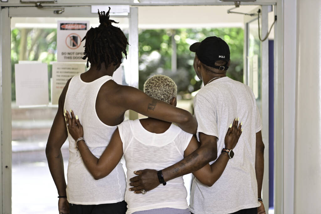Tyson stands with two residents looking out of the front doors of Welcome House. Photo by Kimberly Evans.