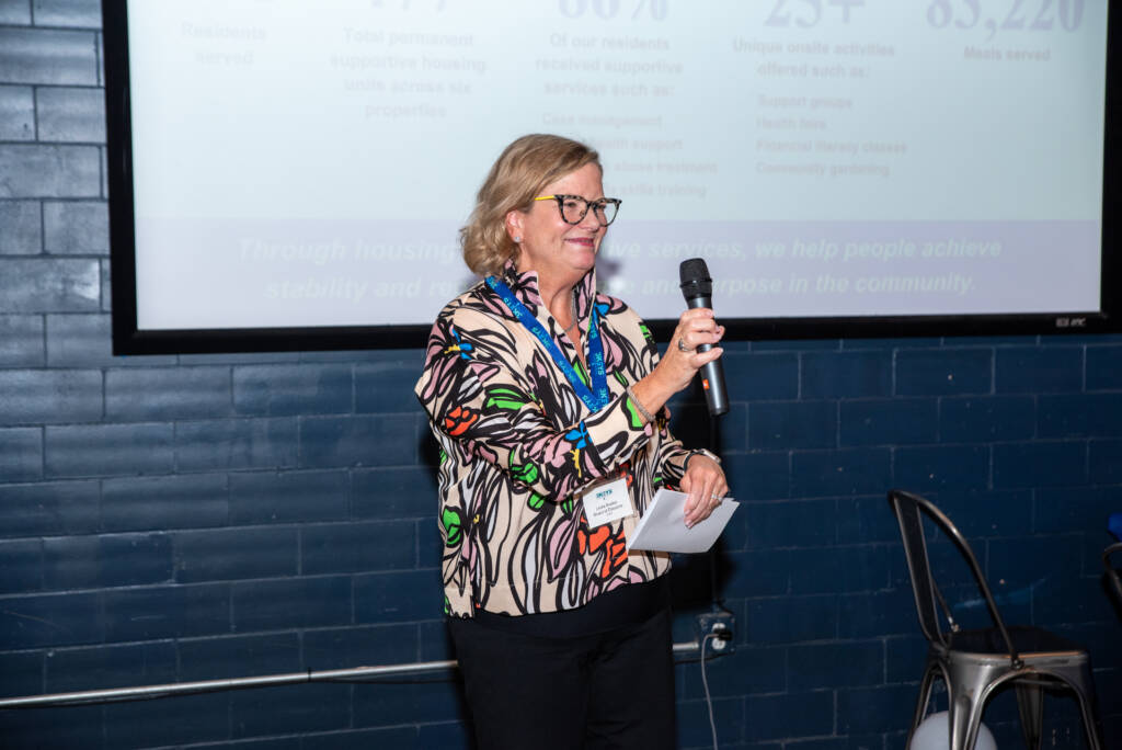 Linda Booker, a 3Keys board member, gives remarks in front of a presentation screen during Cheers for a Cause in 2024.