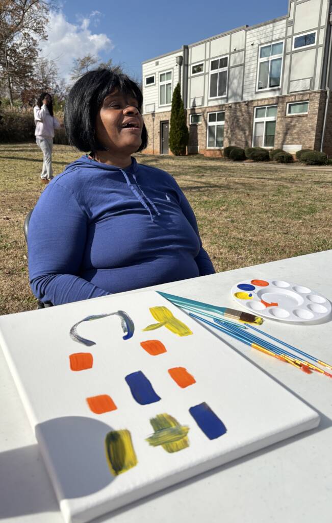 A 3Keys resident paints on a canvas on a table during the 2025 Feed the Hungry event.