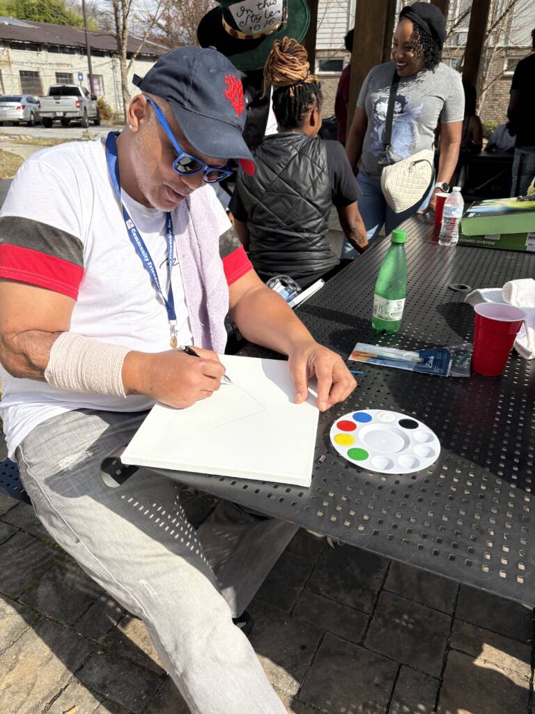 A 3Keys resident paints on a canvas on a table during the 2025 Feed the Hungry.