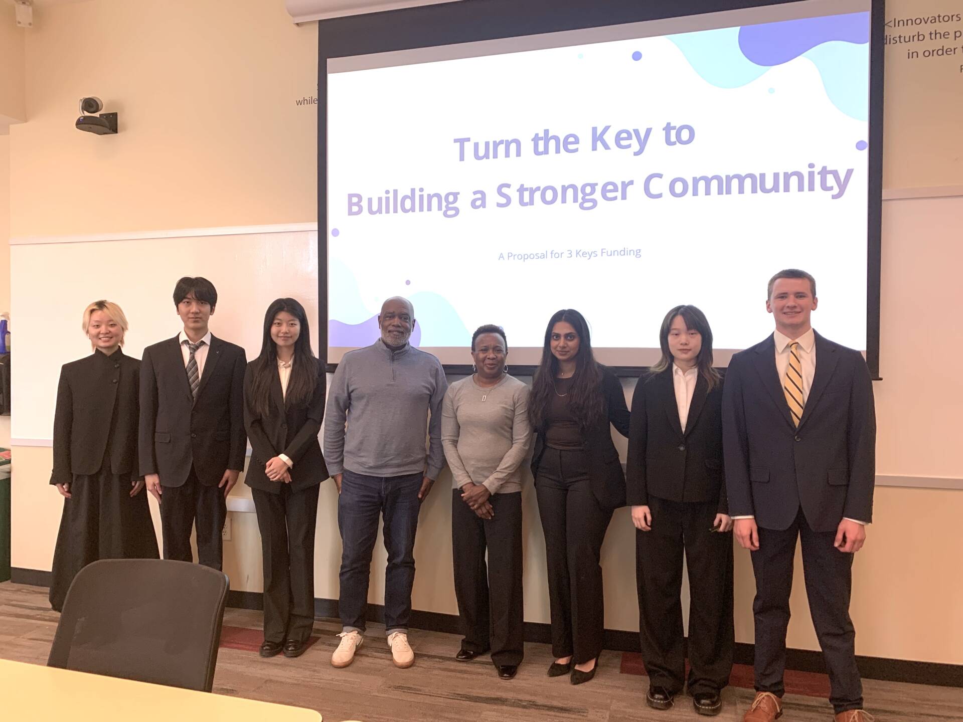 A group of students from Emory University's Goizueta Business School stand in front of their presentation to The 3Keys in Atlanta.